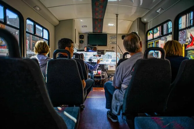 Passengers seated inside a small tour shuttle bus, the driver ahead